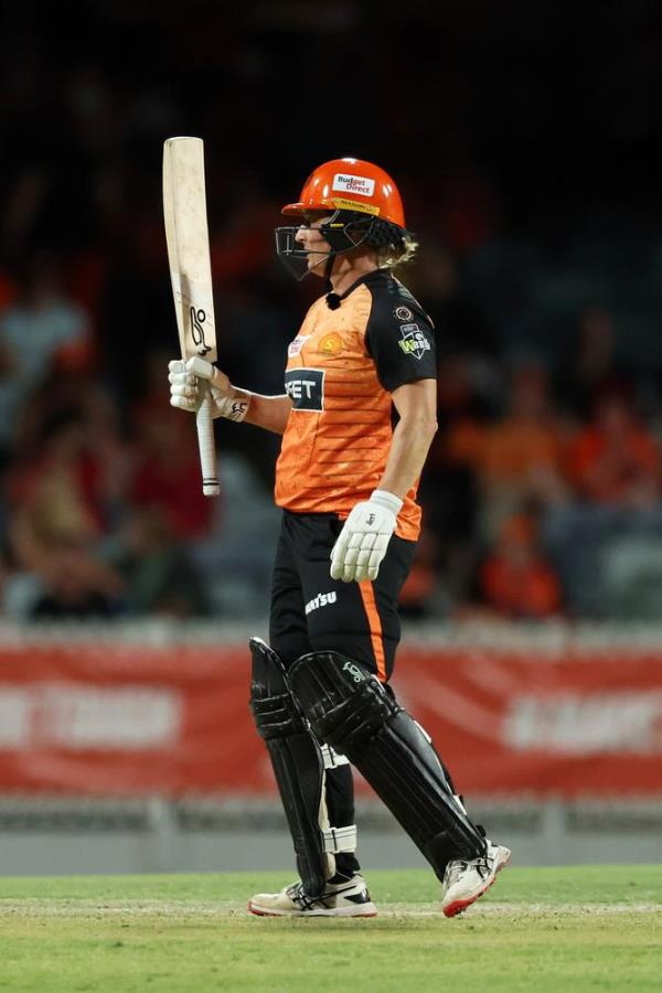 Sophie Devine of the Scorchers raises her bat after scoring fifty runs.