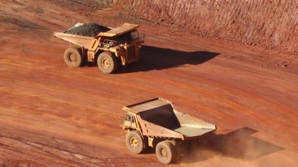 Two haul trucks driving along a road on a minesite.